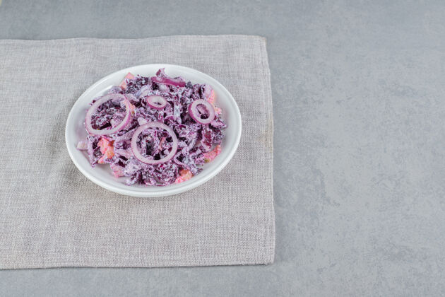 早午餐紫色卷心菜和洋葱沙拉放在白色陶瓷盘子里餐具膳食剁碎
