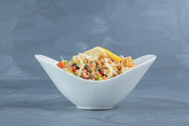 饮食柠檬片放在大理石桌上的一小碗蔬菜沙拉上面混合美味美味