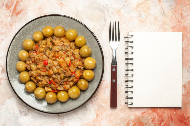 营养烤茄子沙拉和腌李子在盘子叉上的俯视图裸体表面上的笔记本饮食食物裸体