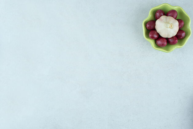 发酵腌山茱萸樱桃和新鲜大蒜一起放在碗里背景文案咸