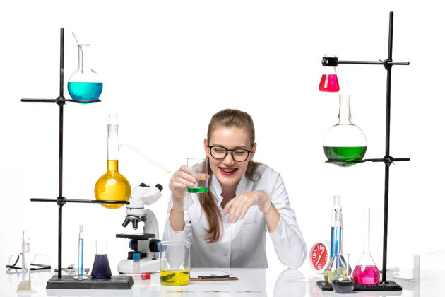 检查前视图穿着医疗服的女化学家检查溶液的气味 在白色背景上大笑化学大流行健康病毒实验室气味玻璃