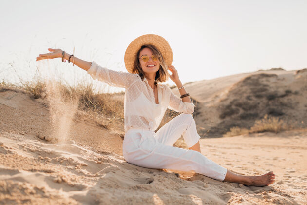 女人穿着白色套装 戴着草帽的沙漠沙滩上的时髦美女阳光优雅冒险