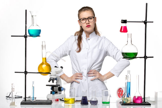 景观前视图穿着医疗服的女化学家正在用不同的溶液工作 在白色背景上摆姿势女化学家套装医生