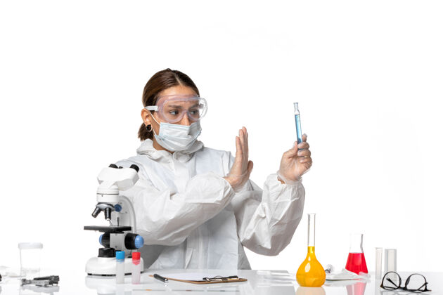 停止正面图：女医生穿着防护服 戴着口罩 拿着装有白色背景病毒溶液的烧瓶——大流行冠状病毒医生病毒实验室