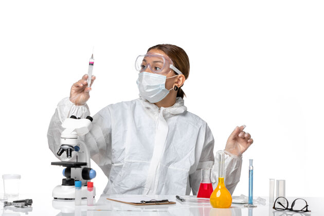 实验室正面图：女医生穿着防护服 戴着口罩 手持白色背景上注射的冠状病毒大流行健康冠状病毒女医生正面外套