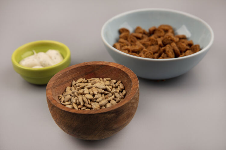 贝壳有机去壳葵花籽的顶视图 放在一个木碗里 上面放着美味的黑麦酱木材种子粮食