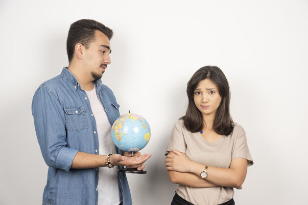 女人男人在怨恨的女孩旁边展示地球仪朋友女人地球仪