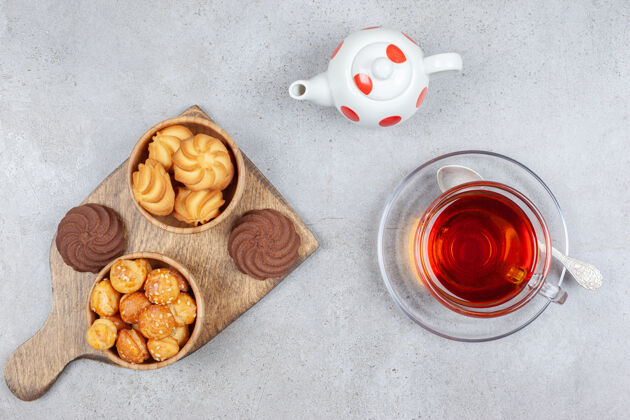 口感在碗里和木板上放饼干 在大理石表面放一杯茶和一个小茶壶食欲茶美味
