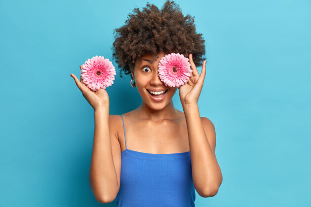 女人女人喜欢芬芳的花朵摘两朵粉红色非洲菊遮住眼睛尽情享受怡人的香气人年轻时尚