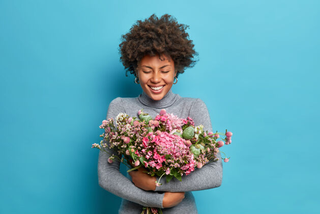 高领毛衣可爱的美国黑人妇女拥抱花束得到春天的花朵人庆祝肖像