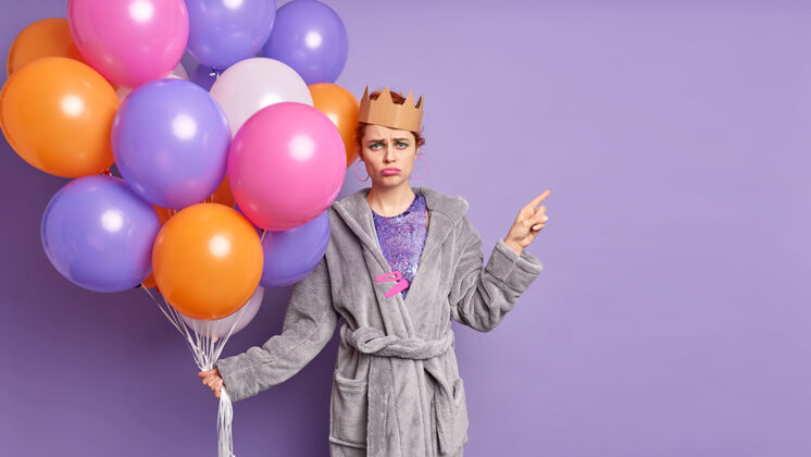 紫色不满失意的寿星脸上有悲伤的表情厌倦了组织节日捧着一堆五颜六色的气球气球不满表情