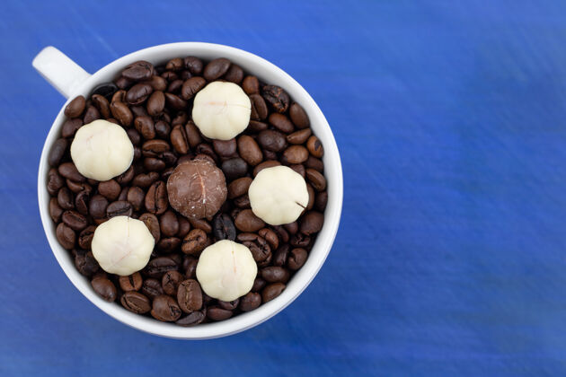 糕点一个装满咖啡豆的白色杯子 蓝色表面有饼干杯子咖啡美味