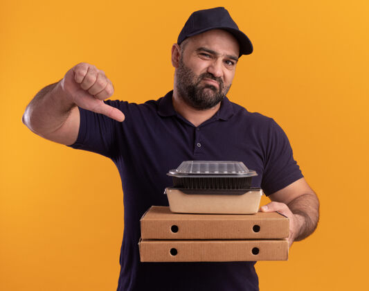 容器一个穿着制服 戴着帽子的中年送货员拿着比萨饼盒上的食物容器 拇指朝下 隔离在黄色的墙上披萨中年帽子