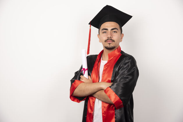 年轻年轻的男生拿着毕业证书在白色衣服上摆姿势表达姿势举行