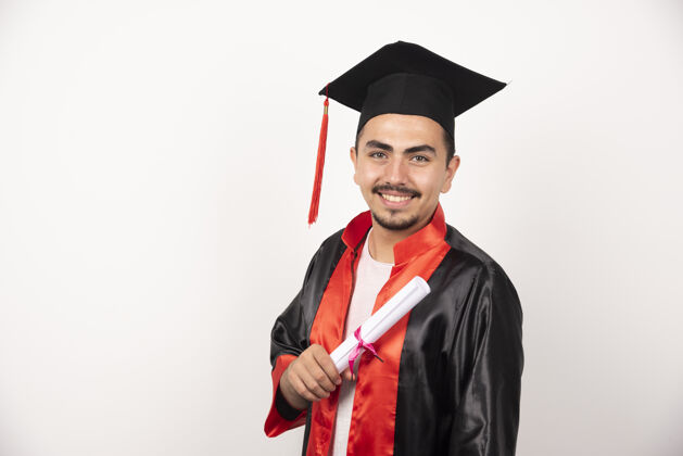 表达快乐的男生拿着毕业证书站在白纸上举行证书帽子