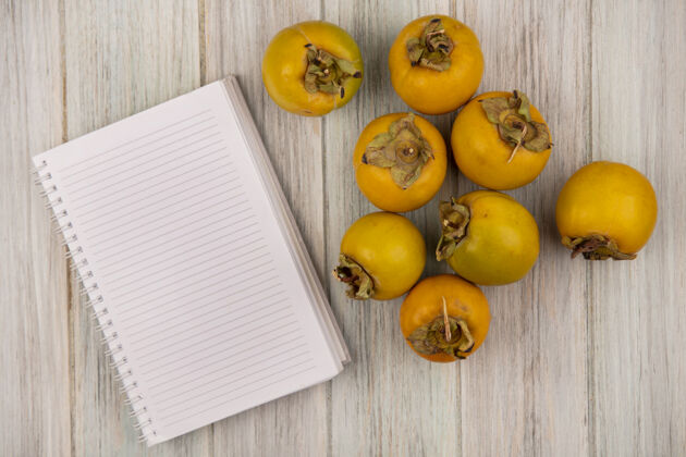 橙黄色柿子果实的俯视图被隔离在一张灰色的木制桌子上 桌子上有复印空间水果新鲜木
