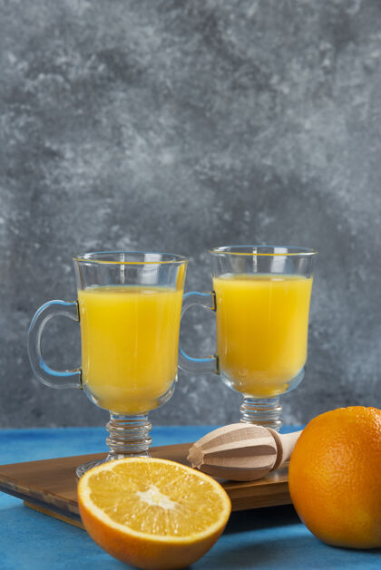 美味在木板上放两杯橙汁水果新鲜柑橘