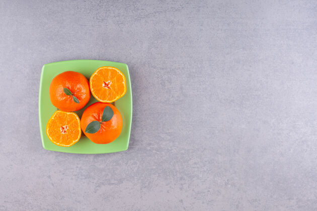 多汁整个橘子和切成片的橘子放在绿色的盘子里切割口味水果