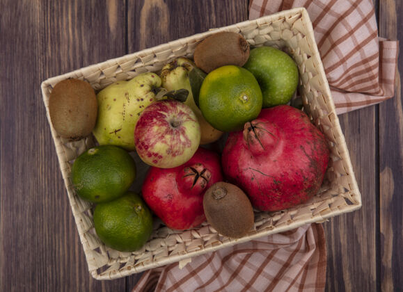 有机木桌上的篮子里放着石榴 橘子 苹果 梨和猕猴桃食品景观石榴