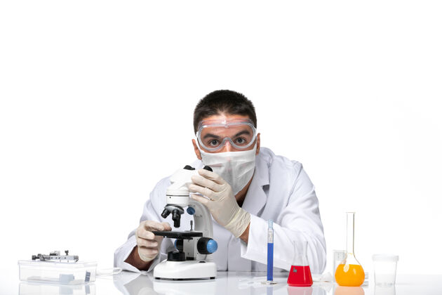 面罩前视图：男医生穿着白色医疗服 戴着面罩 在空白处使用显微镜观察医疗病毒健康