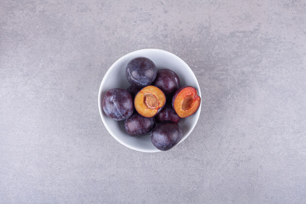 种子一束新鲜的紫李子放在白碗里切块切片水果