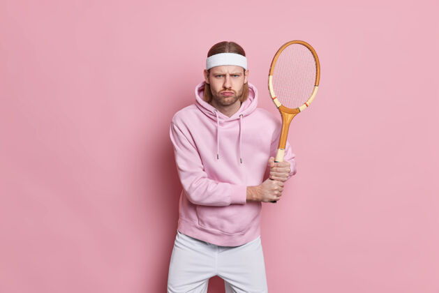 持有认真活跃的运动员用网球拍站着玩最喜爱的游戏 为了健康而参加体育运动一个粉色运动