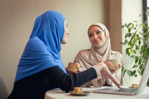 衣服使用设备美丽的阿拉伯女人在咖啡馆或餐厅聚会 朋友或商务会议一起度过时光 交谈 欢笑生活方式时尚快乐的化妆模特伊斯兰肖像漂亮