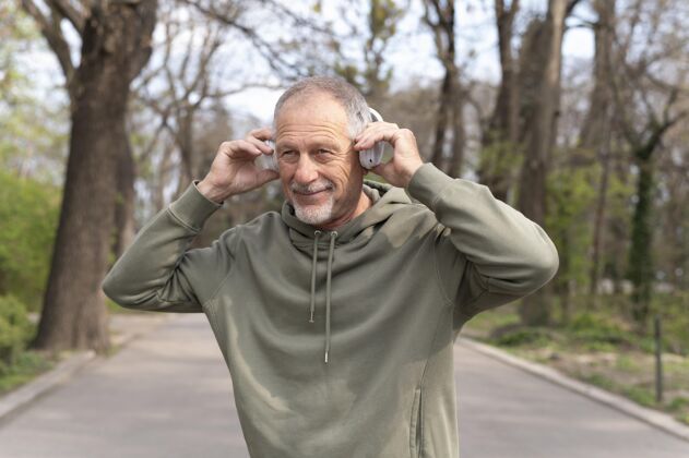 生活方式戴着耳机听音乐的现代老人男人公园休闲