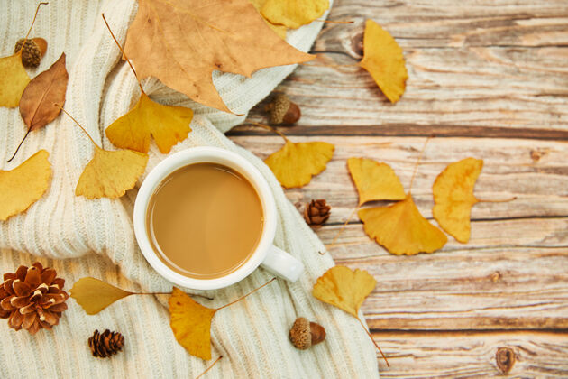 树叶一杯咖啡和秋叶在木制背景上的特写镜头秋天乡村的背景