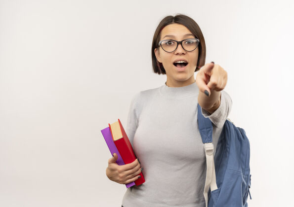 眼镜印象深刻的年轻女学生戴着眼镜 背着书包指着前面的白色孤立的书背学生包