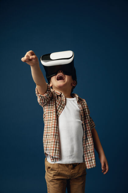 软件与虚假世界作斗争穿着牛仔裤和衬衫的小男孩或儿童 戴着虚拟现实耳机眼镜 与蓝色工作室背景隔离尖端技术的概念 视频游戏 创新儿童虚拟设备视觉