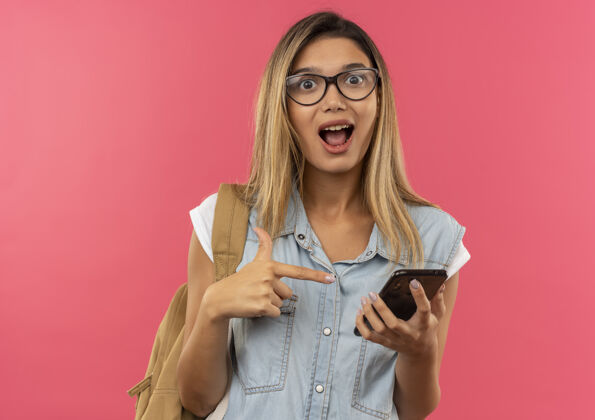 手机印象深刻的年轻漂亮的女学生戴着眼镜 背着书包拿着手机指着粉色的隔离带粉色拿着手机
