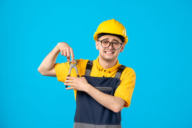 切割工前视图穿着制服和头盔的男建筑工人用钳子在蓝色上割手指修理工建筑工人水管工