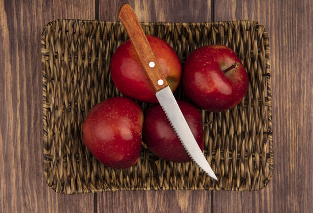 苹果新鲜多汁和红色的苹果在柳条托盘与刀在木制背景俯视图新鲜柳条水果