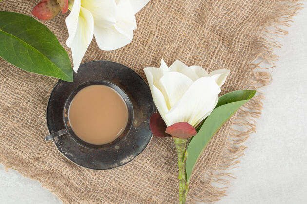 美味的在粗麻布上放一杯浓咖啡和白花热的花粗麻布