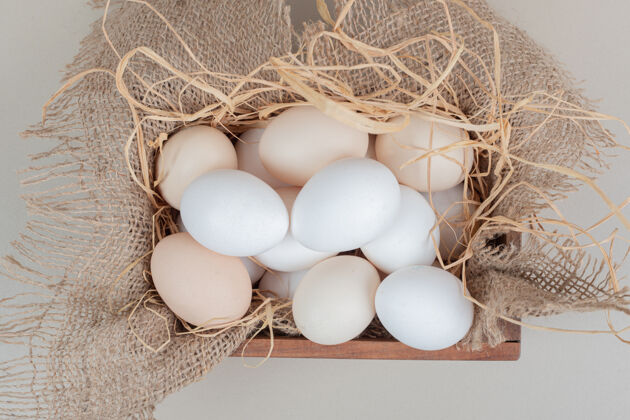 生的新鲜的鸡蛋和干草放在木篮里鸡肉桌布新鲜