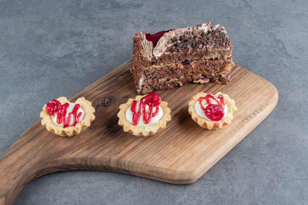 木头在木板上放一块美味的蛋糕和迷你纸杯蛋糕好吃的食物蛋糕