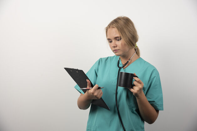 女孩女医生拿着杯子看剪贴板高质量的照片护士人制服