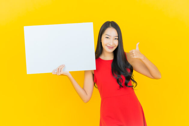 女人一幅美丽的亚洲年轻女子微笑的画像 黄色的墙上挂着白色的广告牌休闲中国人海报