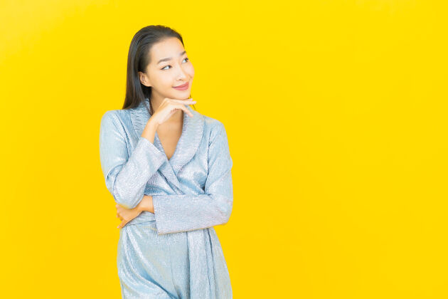 时尚在黄色的墙上描绘美丽的亚洲年轻女子微笑着行动人明亮年轻