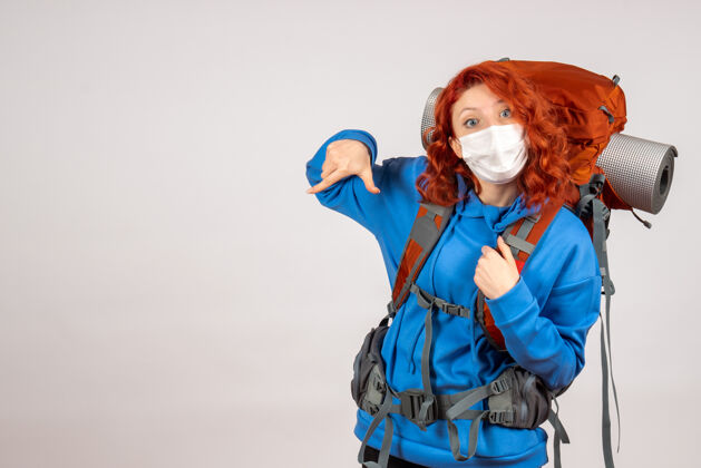 背包戴着面具背着背包的女游客的正面图自然年轻面具