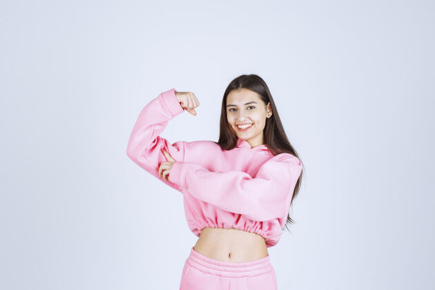 拳头穿着粉色睡衣的女孩展示她的手臂肌肉力量成功休闲
