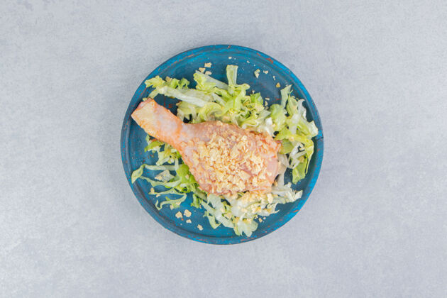 有机把沙拉和鸡腿放在木制盘子里 放在蓝色的表面上家禽美味蔬菜