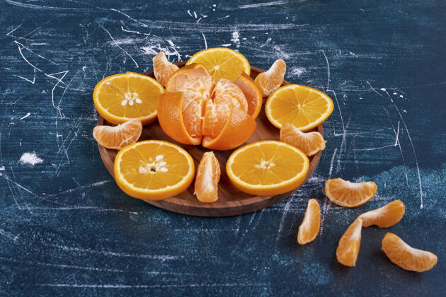 异国情调在蓝色背景的木盘上 把橙子和柑橘片分开高质量的照片素食健康水果