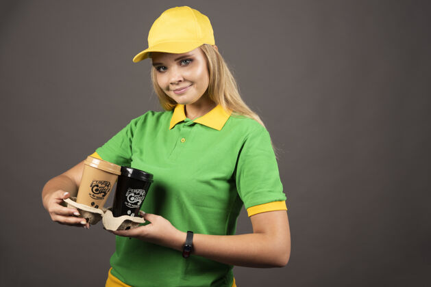 制服女送货员拿着咖啡杯在黑暗的背景高品质的照片送货员人杯子
