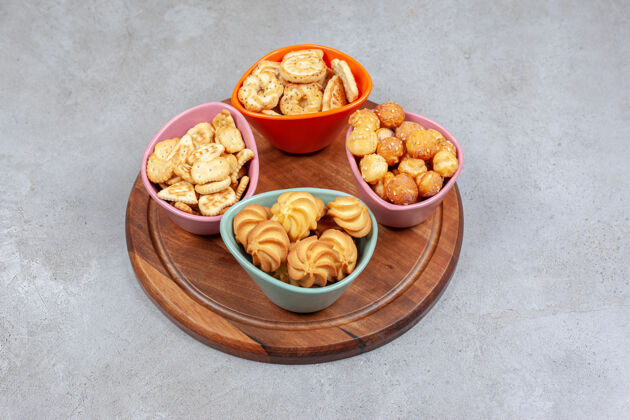 薯片四个五颜六色的碗脆饼干和饼干芯片在木板上大理石背景高品质的照片美味午餐饼干