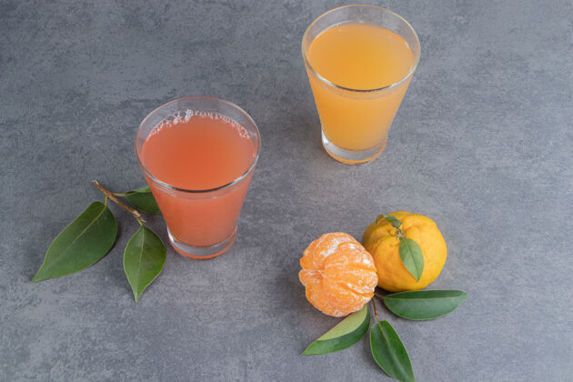 柑橘两杯新鲜的果汁加上叶子和橘子多汁叶子水果