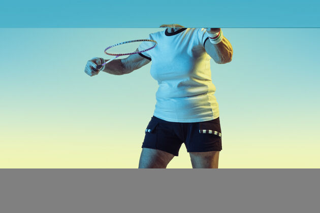 单人资深女子在霓虹灯下穿着运动服在渐变背景上打羽毛球活跃东京姿势