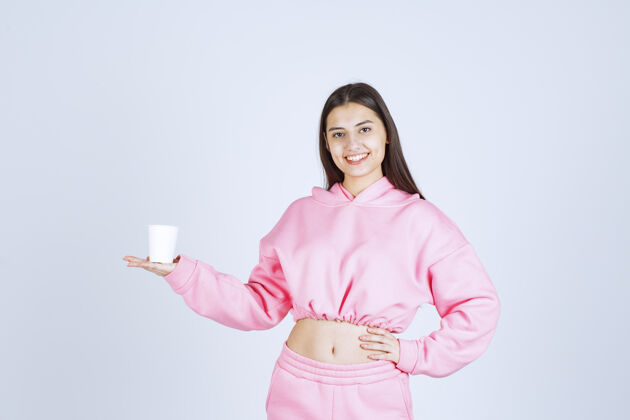 成人穿着粉色睡衣的女孩拿着咖啡杯指着什么东西人类人积极