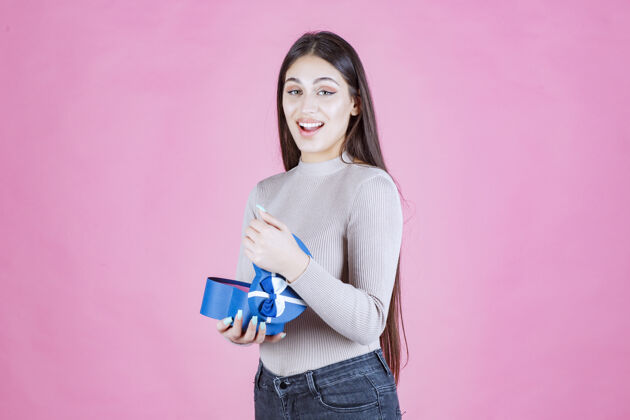 庆祝女孩拿着一个蓝色的礼盒 微笑着人积极女人